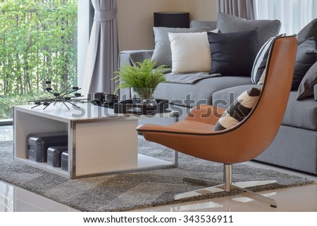 living room with plant in vase and black pattern pillows on modern leather chair