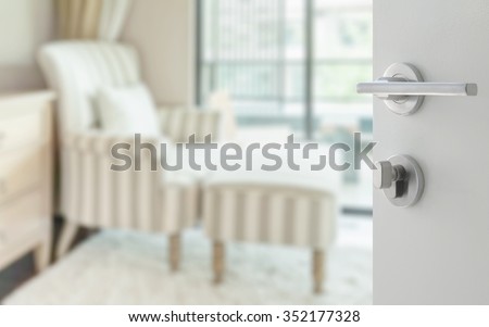 opened white door to striped armchair and ottoman in living room as blur background