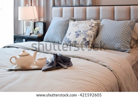 elegant bedroom interior design with floral pattern pillow and and decorative tea set on bed