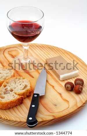 Pate, bread, glass of red wine, hazelnuts and knife a wood plate on white background