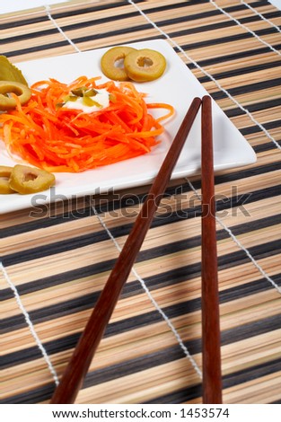 Salad of carrot on a white porcelain plate with sticks