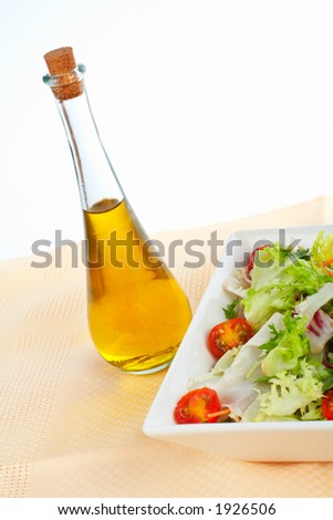 Olive oil bottle and green salad in the bowl