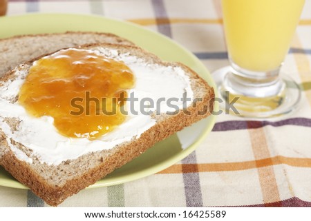 Toast with butter and peach jam in the green plate with soft shadow on square mat background. Shallow depth of field