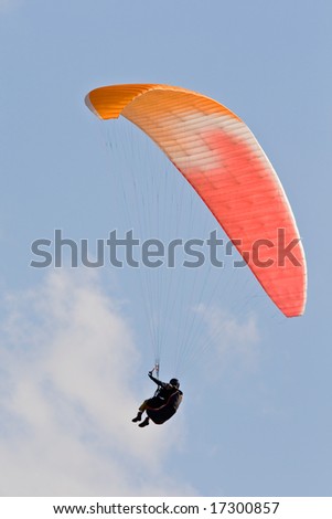 A man with a colorful paraglider flying in the sky