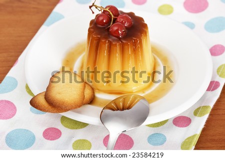Vanilla cream caramel dessert with red currants and two cookies on white dish