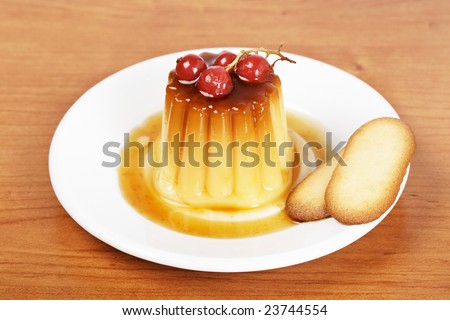 Vanilla cream caramel dessert with red currants and two cakes on white dish