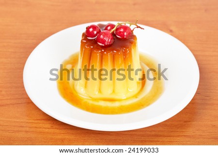 Close-up of a vanilla cream caramel dessert with red currants on white dish