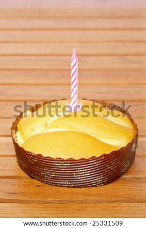 A tasty cake cream with candle isolated on wooden background. Shallow depth of field