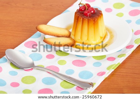 Vanilla cream caramel dessert with red currants and two cookies on white dish. Shallow depth of field