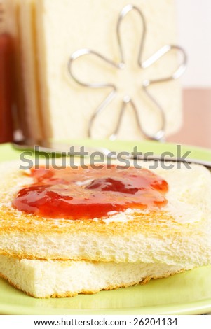 Toast with butter and strawberry jam glass jar in the plate with soft shadow on square mat background. Shallow depth of field