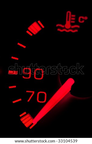 Car dashboard gauges illuminated over a black background. Shallow depth of field