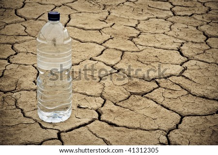 A water bottle on dry and cracked ground in the desert. Shallow depth of field