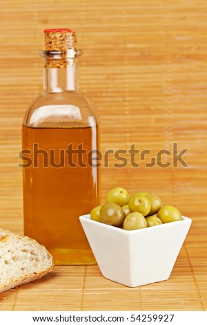 Bread, olive oil bottle and some olives on wooden background. Shallow depth of field