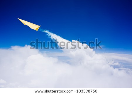 Yellow paper plane flying over clouds against blue sky