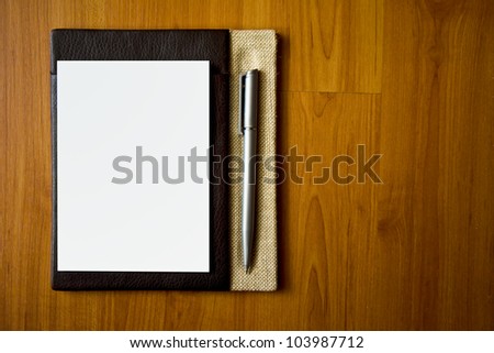 Leather notepad with paper and pen on wood desk