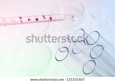 Laboratory pipette with drop of chemical liquid  over glass test tubes
