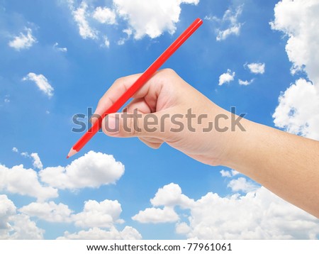 Hand holding color pencil against blue sky