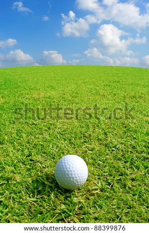 Golf ball on green grass with clear blue sky