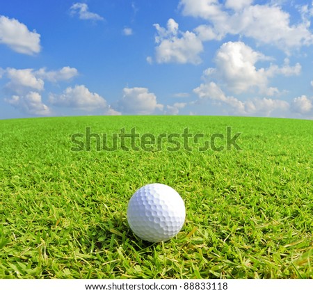 Golf ball on green grass with clear blue sky