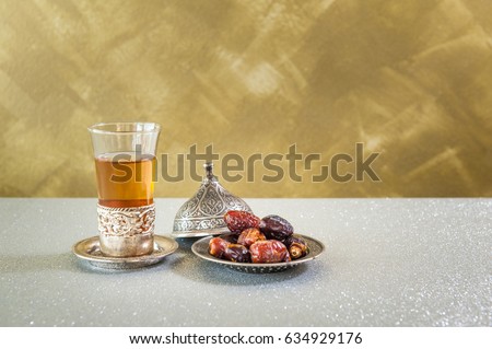 Islam kurma, ramadan, date palm fruits and Tea on a metal tray placed on a glitter sparkle background.
