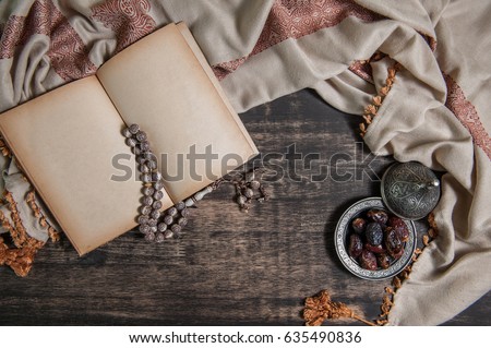 Islam holy old book of Muslims, Date-palm is placed on silver. date palm fruits or kurma, ramadan on a wooden black background.