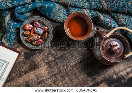 Islam holy book of Muslims, Date-palm is placed on silver. date palm fruits or kurma, ramadan on a wooden black background.
