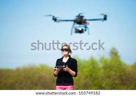 Young woman flying remote control helicopter in countryside.