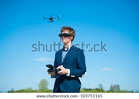 Young man wearing video glasses gets a first person view from video piloting as he holds a transmitter for a remote controlled helicopter.