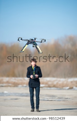 Young man flying remote controlled helicopter or Hexa copter outdoors.