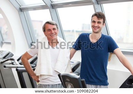 young man and his father training in the gym, laughing, treadmill
