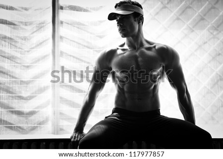 artistic shot, black and white, of a young bodybuilder posing in the gym