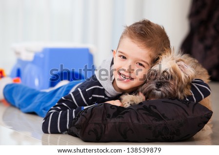 little kid holding his pet at home, five years old child playing with his dog in the living room, smiling, laughing