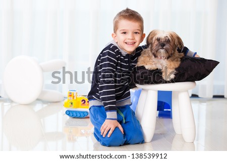little kid holding his pet at home, five years old child playing with his dog in the living room, smiling, laughing