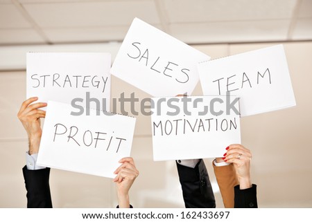creative photo: five hands holding card boards in the air: strategy, motivation, profit, team, sales