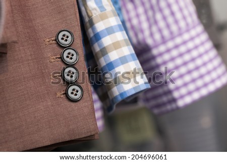 Closeup of the sleeves of a brown man coat and two blue and purple man shirts in a store or warehouse