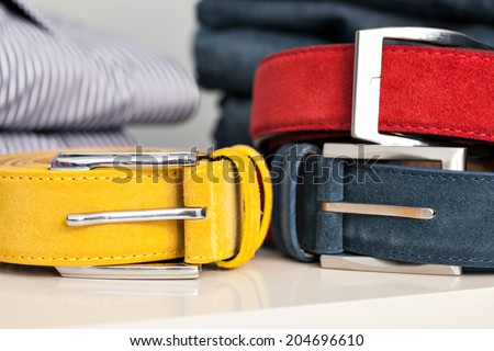 Display of bright colored man belts in a shop or showroom: yellow, red and blue