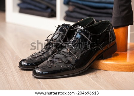Display of a pair of black lacquered leather man shoes in a store or showroom