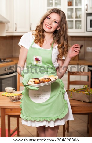 Beautiful woman wearing an apron and serving someone with cookies; woman wearing a kitchen apron saying \