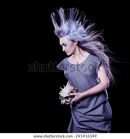 dark fashion shot of a woman holding a evil skull, crazy hairstyle with feathers