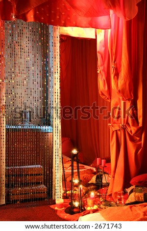 bedroom sensual environment with candles, glass pearls, red curtain and mirror