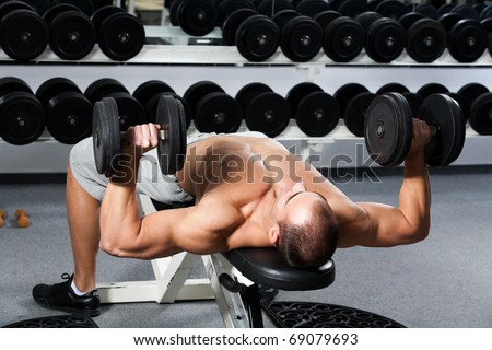 young bodybuilder training in the gym: dumbbell bench press - start position