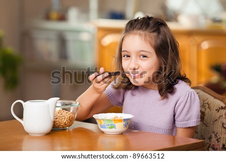 little girl having breakfast: cereals with milk