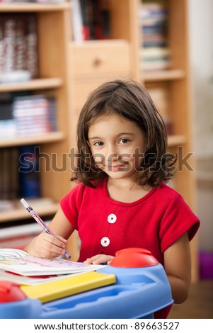 little girl drawing on her book at playtable