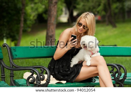 young fashion woman in the park with her dog, checking her phone