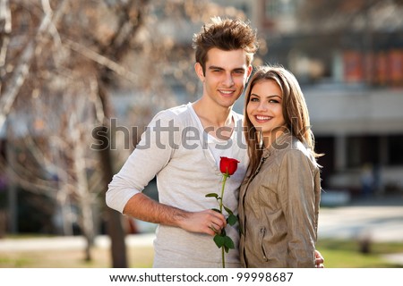romantic moment: young man giving a rose to his girlfriend