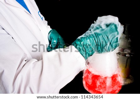 Scientist holding a glass beaker with red chemical and vapors