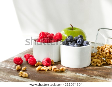 Healthy snack foods with raspberries, blueberries, green apple and walnuts