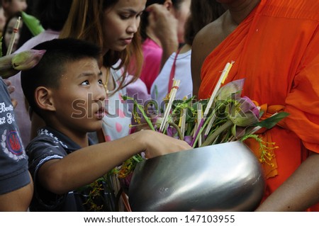 SARABURI, THAILAND-JULY 23: An unidentified child and lady offers flowers to Buddhist monk ceremony at Phrabuddhabat temple on July 23, 2013 in Saraburi, Thailand.
