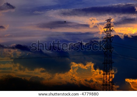A rich sunset of golds, oranges and blues is the backdrop for this silouetted transmission tower.