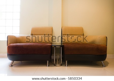 A pair of chairs with table in the middle.